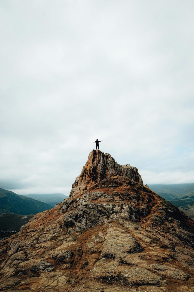 pexels-photo-8970411-8970411 Person raises arms on a rocky mountain peak, symbolizing freedom and achievement.